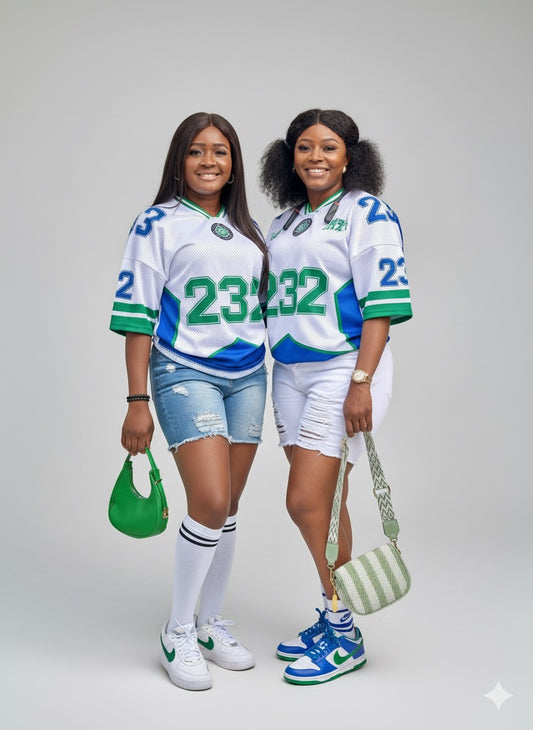 Two women wearing matching sports jerseys with the number 23 on a plain background