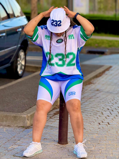 Person wearing a sports outfit with numbers and letters, standing on a sidewalk.