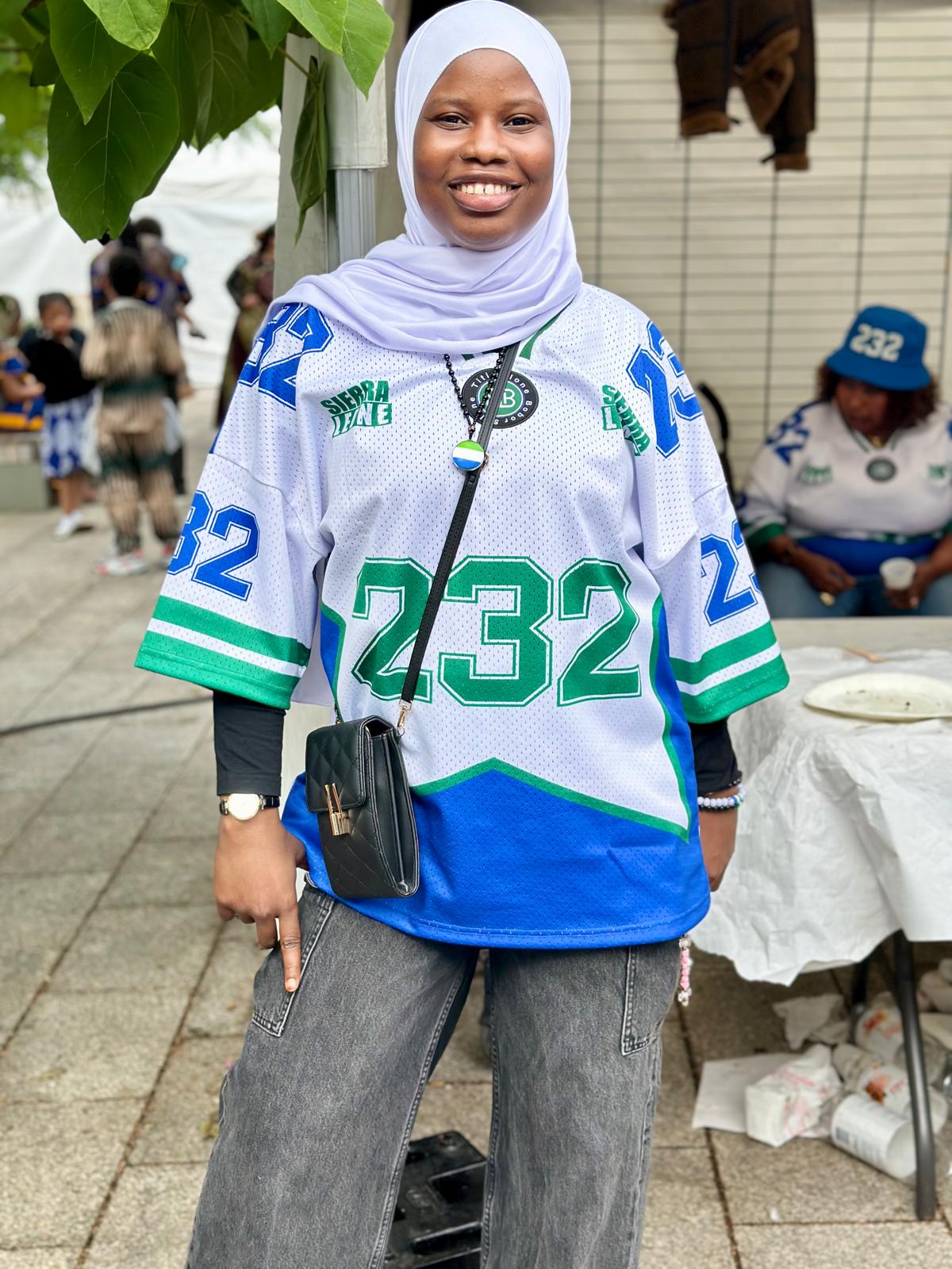 Person wearing a sports jersey with numbers, standing outdoors.