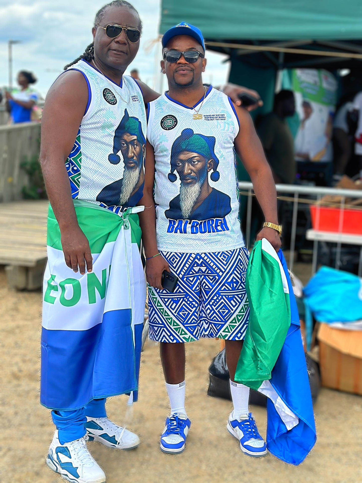Two people wearing matching outfits with a graphic of a man and text, standing outdoors.