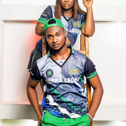 A man and a woman wearing sports jerseys with embroidered logos, sitting in front of a grey background.