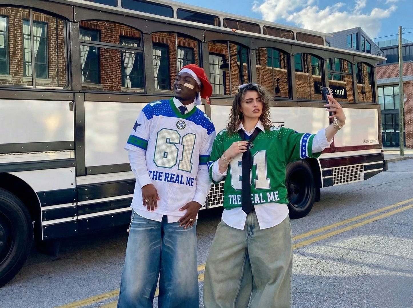 Two people wearing matching jerseys in front of a bus.