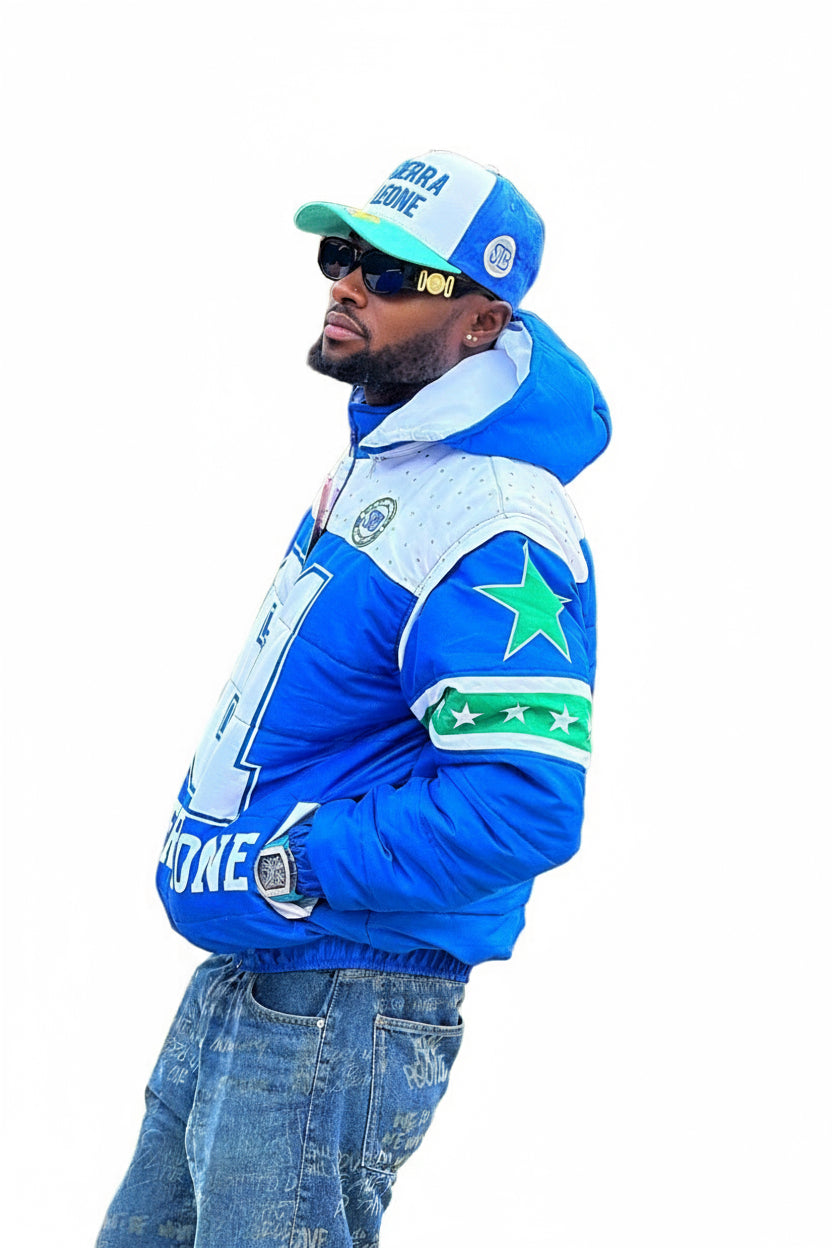 Man wearing a blue jacket with star design, cap, and sunglasses on a white background