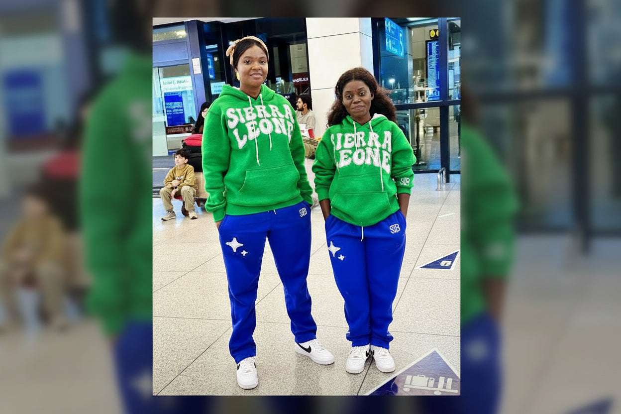 Two people wearing matching green 'Sierra Leone' hoodies and blue pants in an indoor setting.