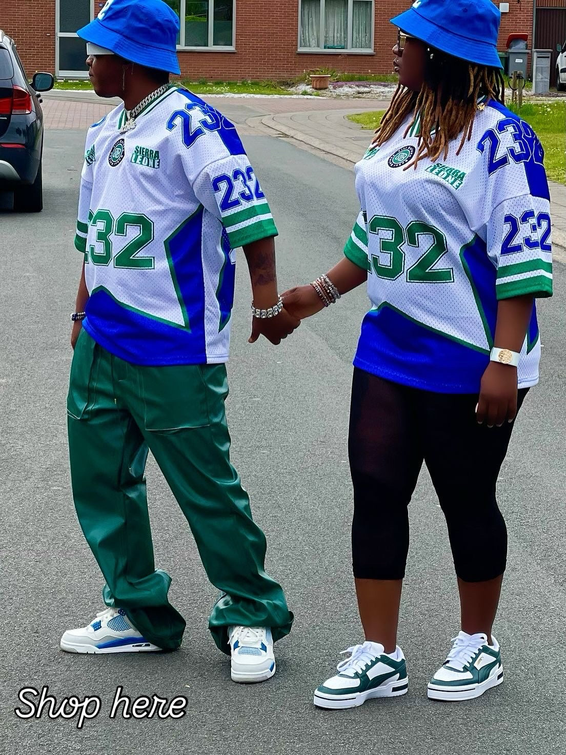 Two people wearing matching sports jerseys with the number 232 on a street.